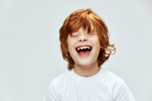 Smiling red haired boy on white background